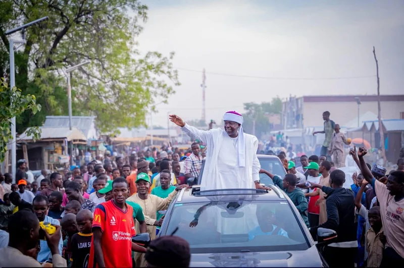 A wide view of a street gathering around a vehicle.